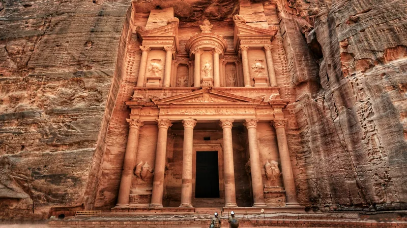 The carved facade of the Treasury at Petra with visitors below for scale