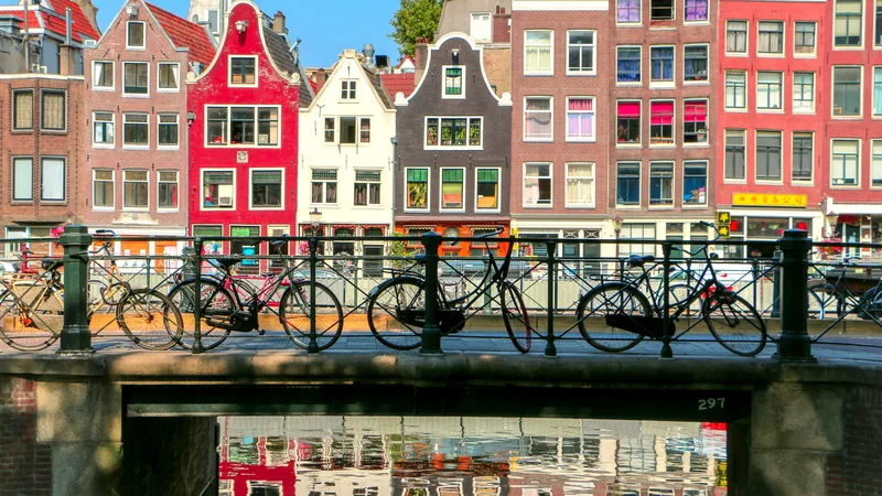 Colourful gabled canal houses behind a bridge lined with bicycles