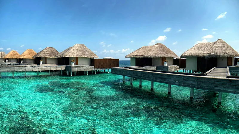 Thatched overwater villas standing above a turquoise lagoon