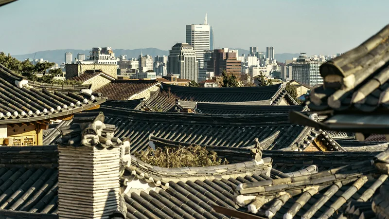Tiled hanok rooftops in Bukchon with the modern city rising behind