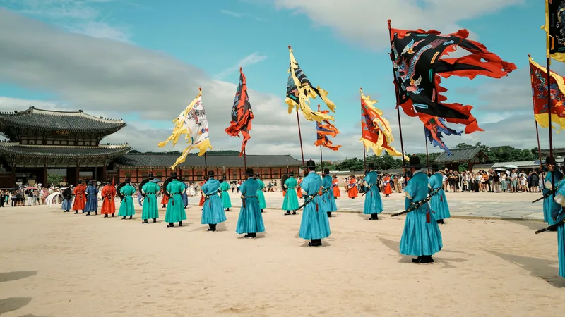 Guards in turquoise robes with flags at the Gyeongbokgung Palace courtyard