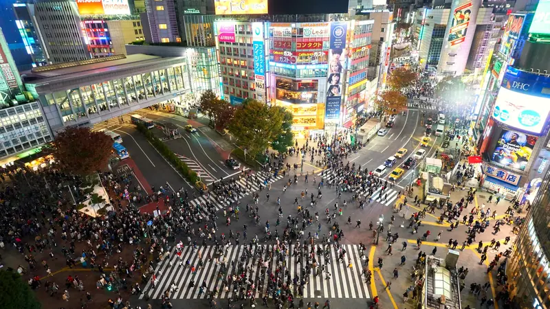 Crowds crossing the Shibuya scramble beneath lit signage